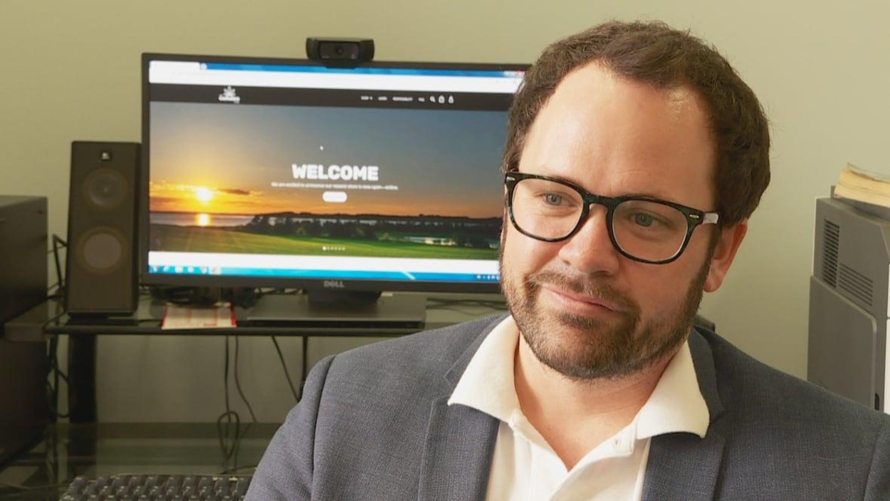 Un homme portant des lunettes et un écran d’un ordinateur au fond avec l’inscription « Welcome ». Un homme portant des lunettes et un écran d’un ordinateur au fond avec l’inscription « Welcome ».