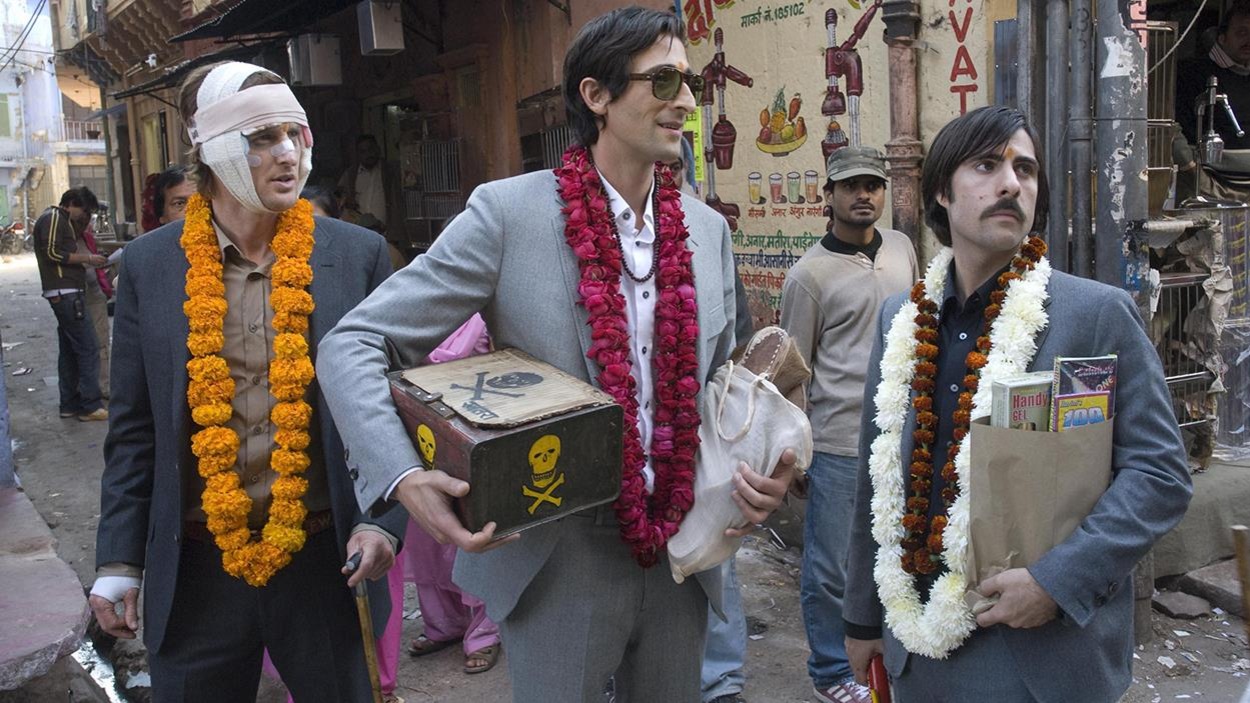 Trois hommes en complets sombres avec des colliers de fleurs dans une rue en Inde, l'un la tête bandée Trois hommes en complets sombres avec des colliers de fleurs dans une rue en Inde, l'un la tête bandée