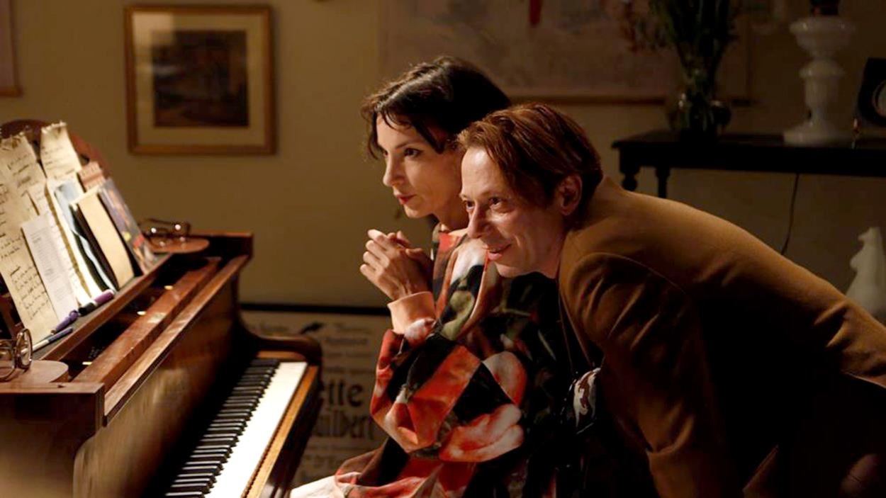Une femme assise à un piano et un homme penché derrière et vers elle. Une femme assise à un piano et un homme penché derrière et vers elle.