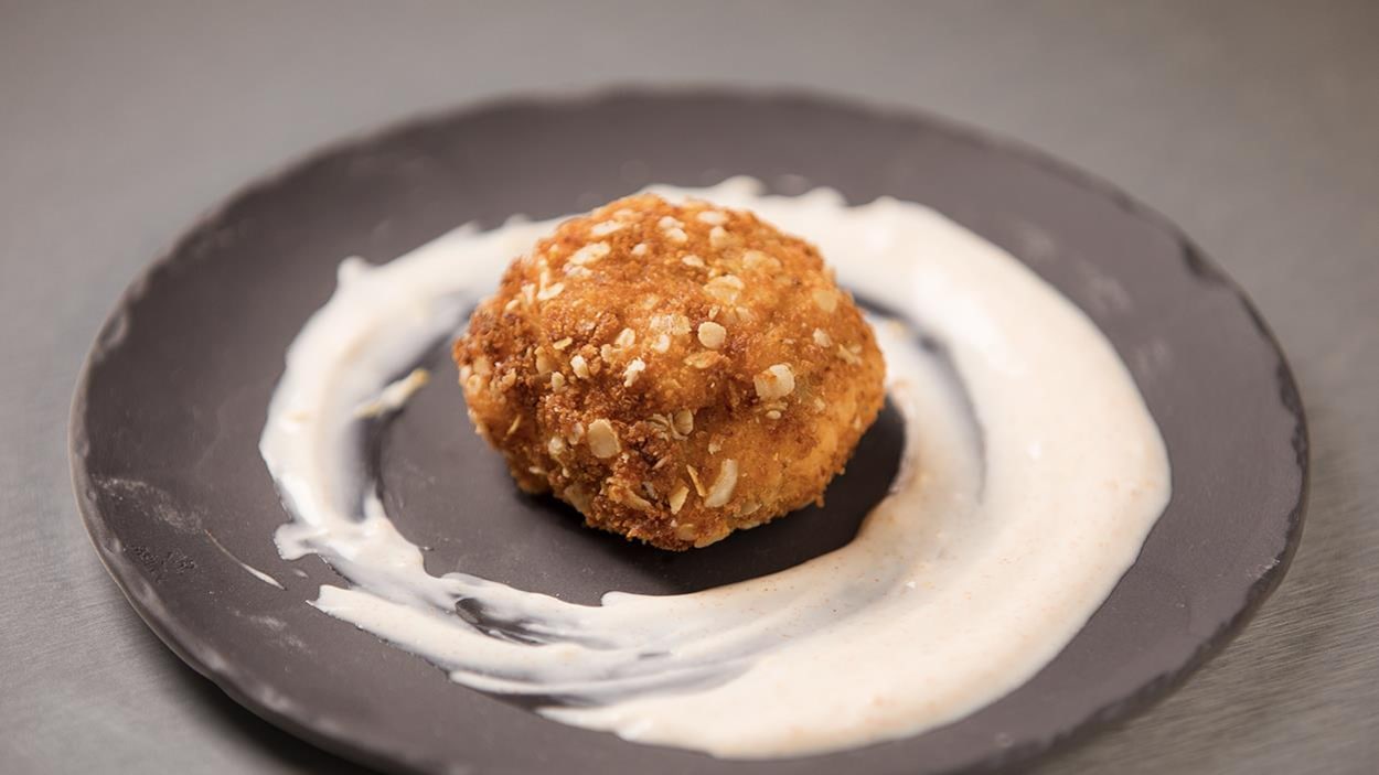 Une boule de cake de homard au centre d'une assiette avec un coulis de yogourt au citron et paprika. Une boule de cake de homard au centre d'une assiette avec un coulis de yogourt au citron et paprika.