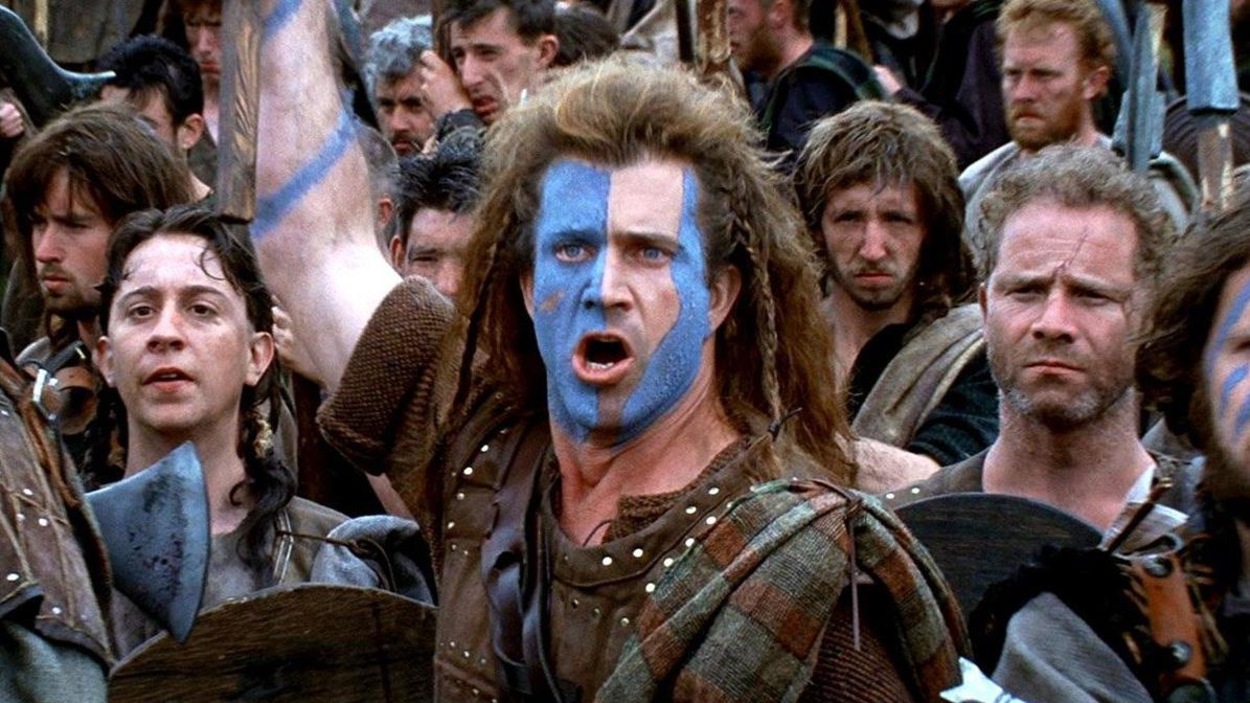Un homme, le visage peint en bleu (Mel Gibson) devant des hommes armés, portant un plaid. Un homme, le visage peint en bleu (Mel Gibson) devant des hommes armés, portant un plaid.