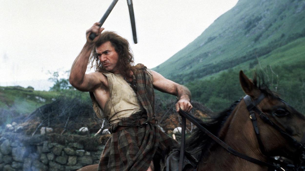 Un homme (Mel Gibson) portant armes et tartan, à cheval, prêt au combat. Un homme (Mel Gibson) portant armes et tartan, à cheval, prêt au combat.