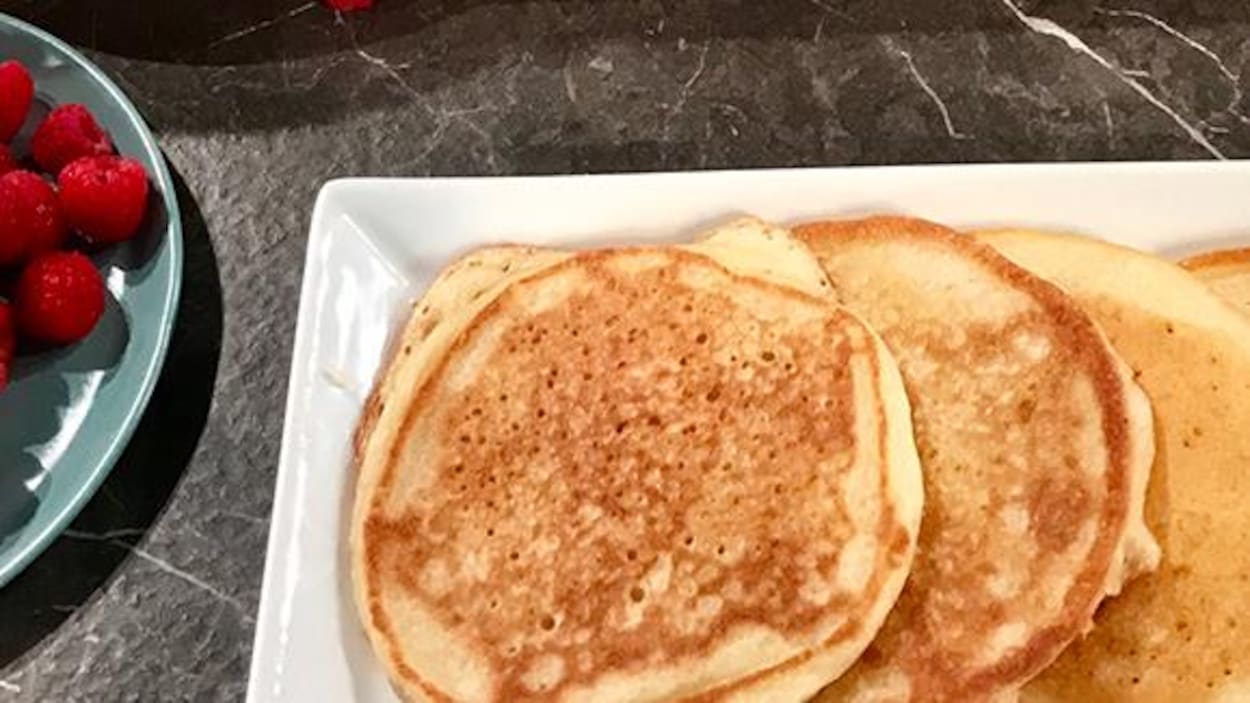 Des crêpes dans une assiette rectangulaire, une assiette de fraises et une assiette de framboises. Des crêpes dans une assiette rectangulaire, une assiette de fraises et une assiette de framboises.
