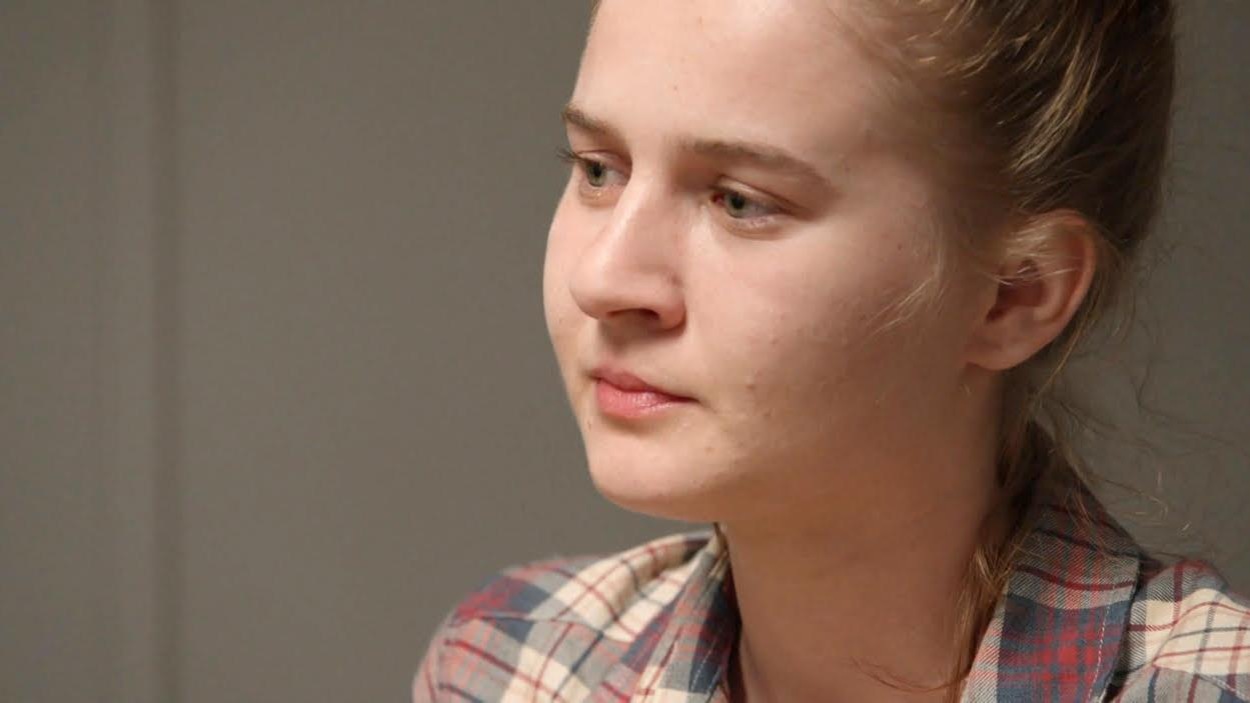 Une jeune femme qui porte une chemise à carreaux.