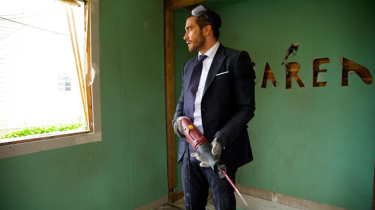 Un homme en costume, des lunettes de protection sur le crâne et un fusil à colle, dans une maison détruite. Un homme en costume, des lunettes de protection sur le crâne et un fusil à colle, dans une maison détruite.