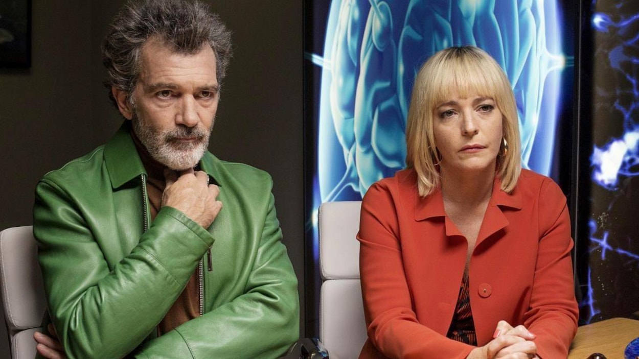 Un homme (Antonio Banderas) en veste verte, assis à côté d'une femme en veste rouge, tous deux devant des images médicales. Un homme (Antonio Banderas) en veste verte, assis à côté d'une femme en veste rouge, tous deux devant des images médicales.