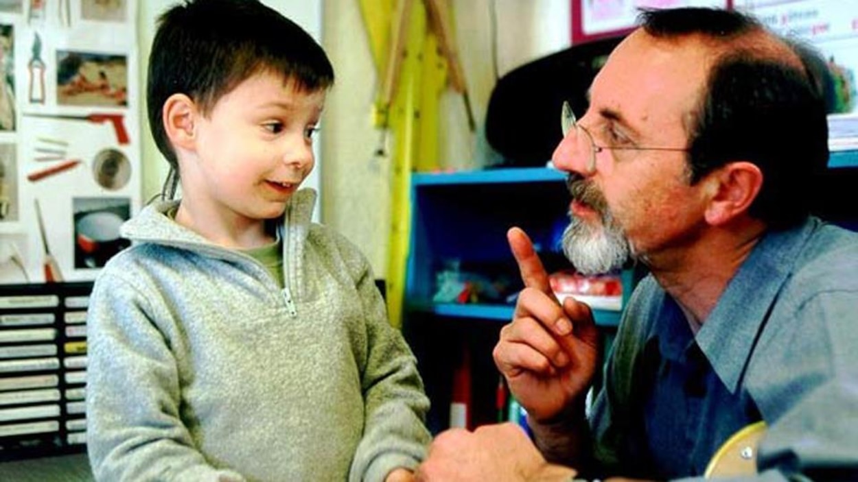 Un instituteur agenouillé à côté d'un jeune élève. Un instituteur agenouillé à côté d'un jeune élève.