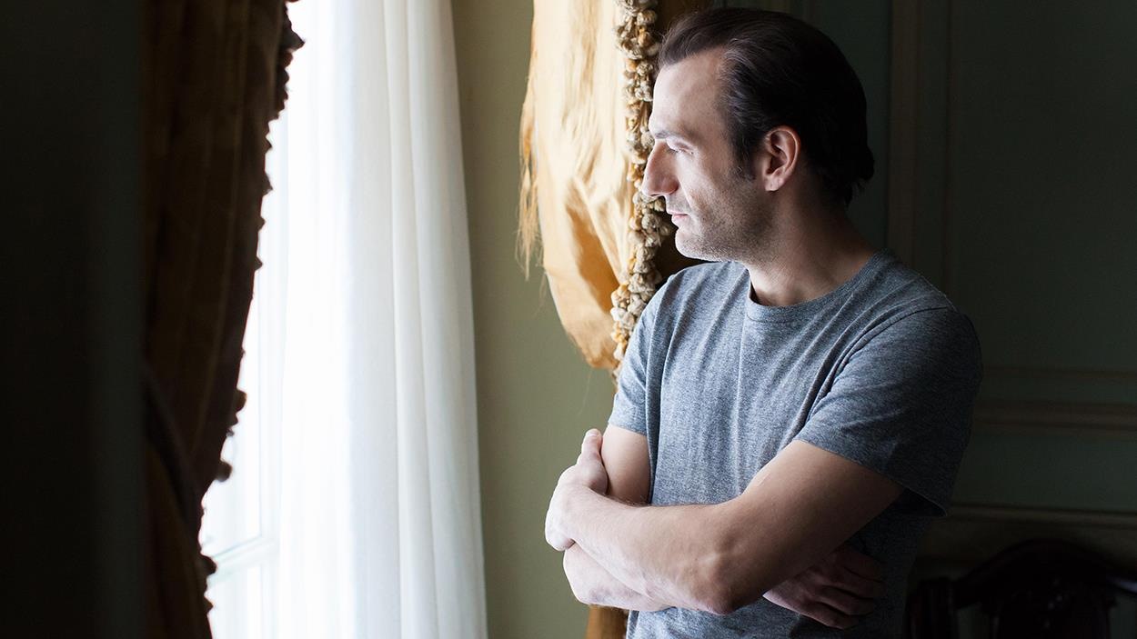 Un homme (Martin Dubreuil), les bras croisés, regarde d'un air triste par la fenêtre. Un homme (Martin Dubreuil), les bras croisés, regarde d'un air triste par la fenêtre.