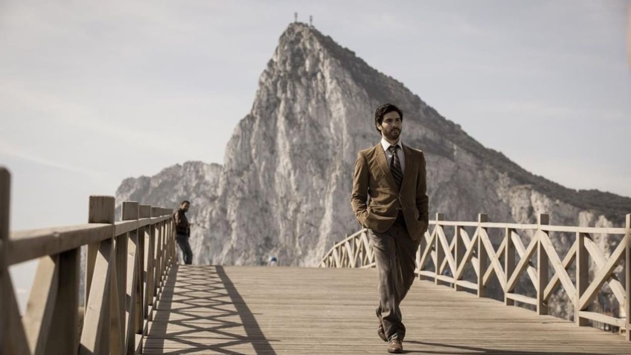 Devant une montagne, un homme (Tahar Rahim) s'éloigne en marchant sur un pont en bois. Devant une montagne, un homme (Tahar Rahim) s'éloigne en marchant sur un pont en bois.