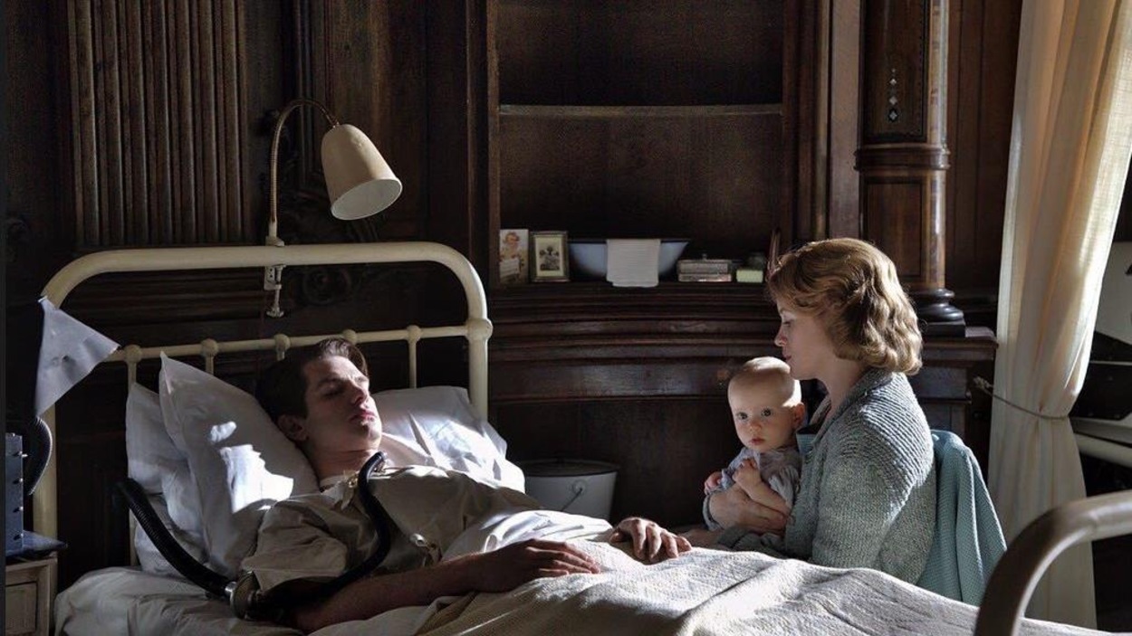 Une femme (Claire Foy), un bébé sur les genoux, est assise auprès d'un homme (Andrew Garfield) dans un lit d'hôpital.
