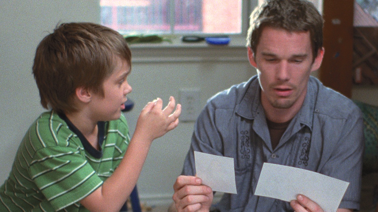 Un petit garçon assis à côté d'un homme (Ethan Hawke) qui regarde des photos. Un petit garçon assis à côté d'un homme (Ethan Hawke) qui regarde des photos.