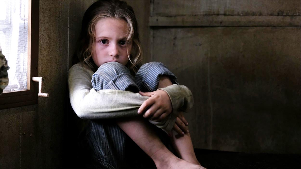 Une petite fille assise les bras repliés autour des genoux, l'air effrayé. Une petite fille assise les bras repliés autour des genoux, l'air effrayé.