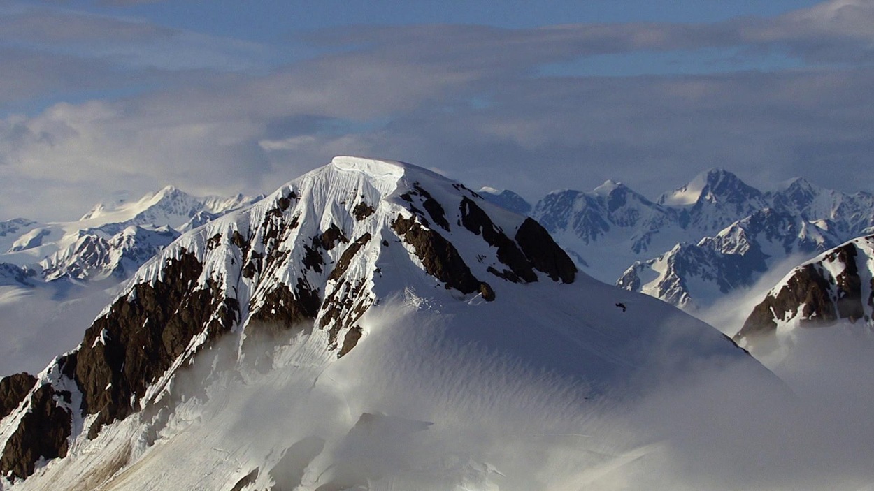 Vue à vol d'oiseau d'une chaîne de très hautes montagnes enneigées.