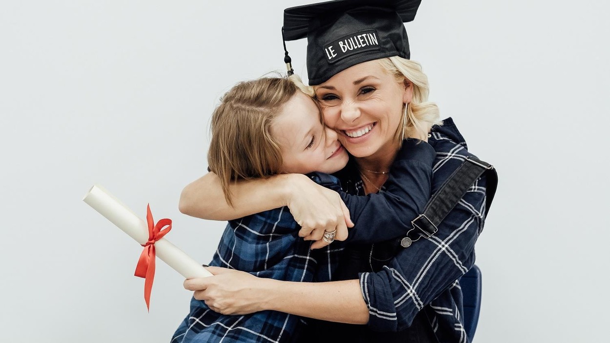 Mariloup Wolfe, un chapeau de diplômé sur la tête, tient son enfant dans ses bras Mariloup Wolfe, un chapeau de diplômé sur la tête, tient son enfant dans ses bras