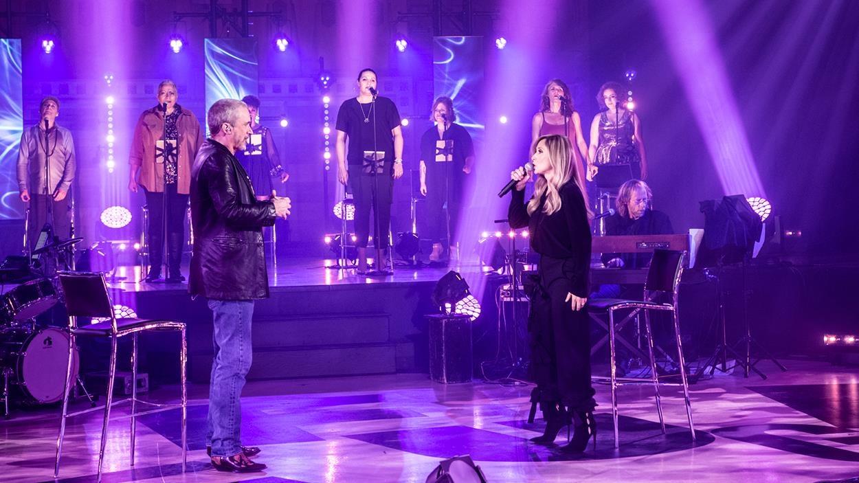Dan Bigras Lara Fabian qui chantent sur la scène, entourés d'artistes. Dan Bigras Lara Fabian qui chantent sur la scène, entourés d'artistes.