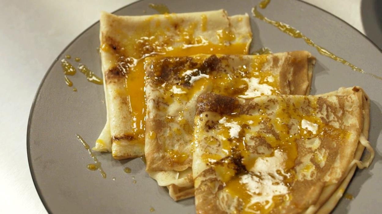 3 crêpes fines aromatisées au miel et à l’argousier dressées sur une assiette. 3 crêpes fines aromatisées au miel et à l’argousier dressées sur une assiette.
