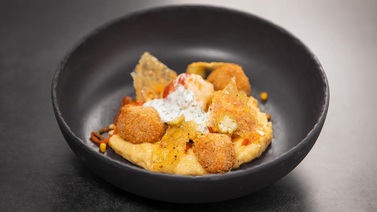 Alligator et homard glacé, garnis d'une tuile de polenta, le tout servi dans un bol rond en terre cuite noire. Alligator et homard glacé, garnis d'une tuile de polenta, le tout servi dans un bol rond en terre cuite noire.