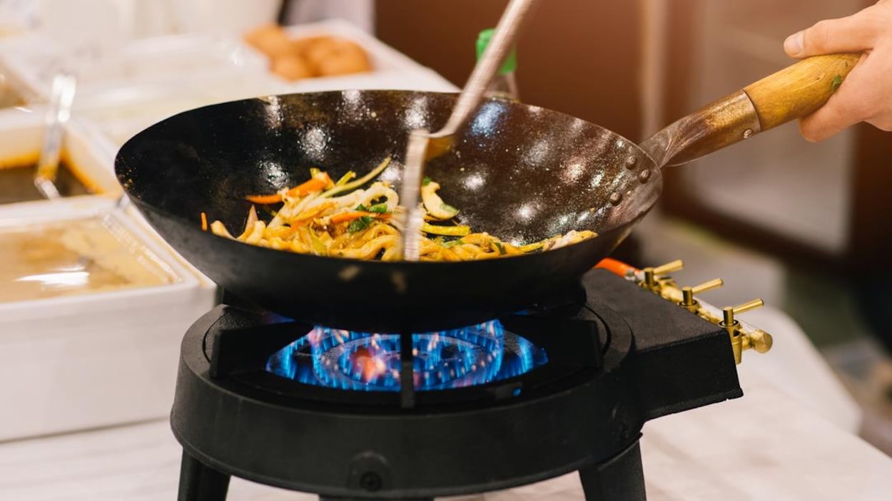 Un chef qui fait sauter des légumes dans un wok. Un chef qui fait sauter des légumes dans un wok.