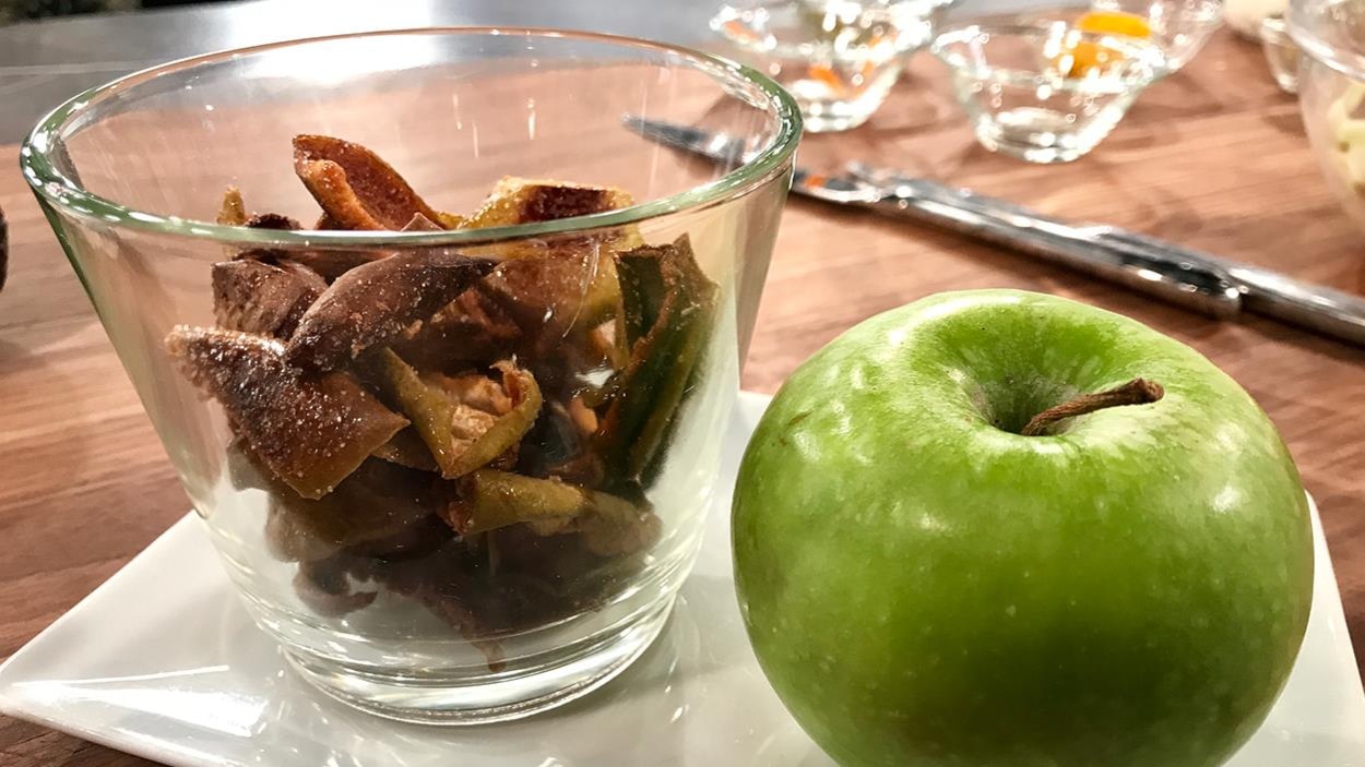 Des croustilles de pommes dans un petit bol et une pomme verte