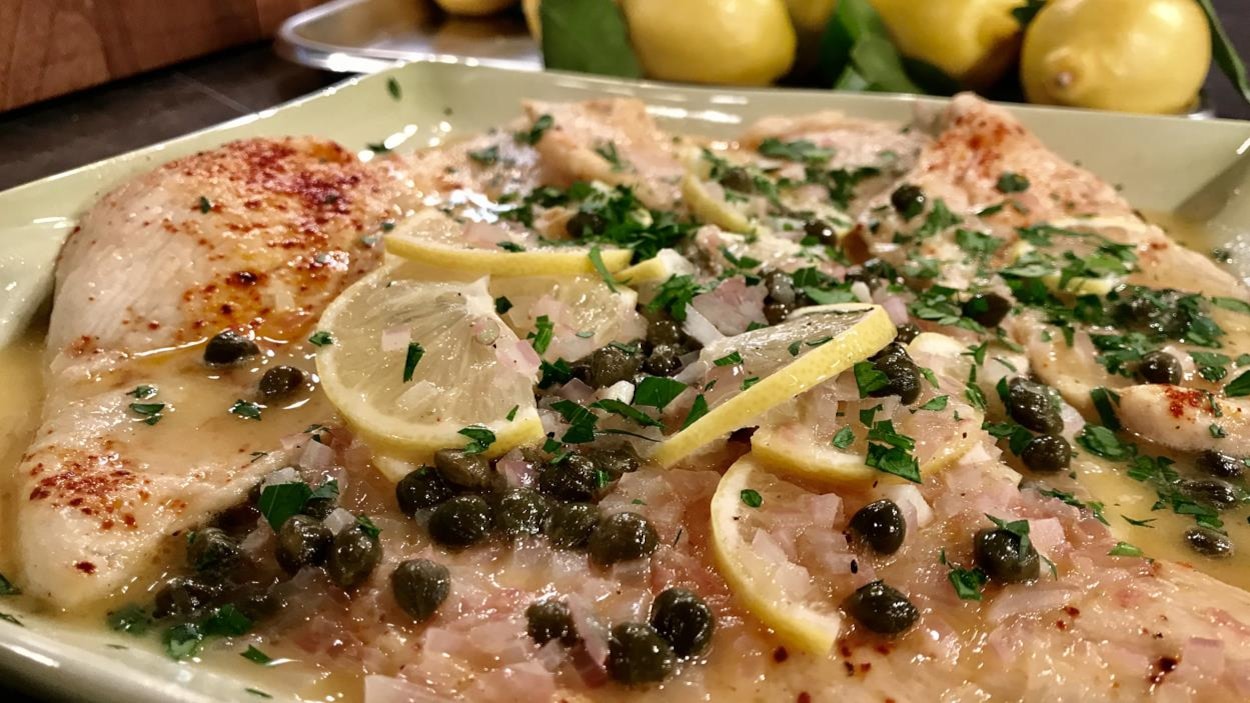 Un plat de poulet garni de câpres et de citron.