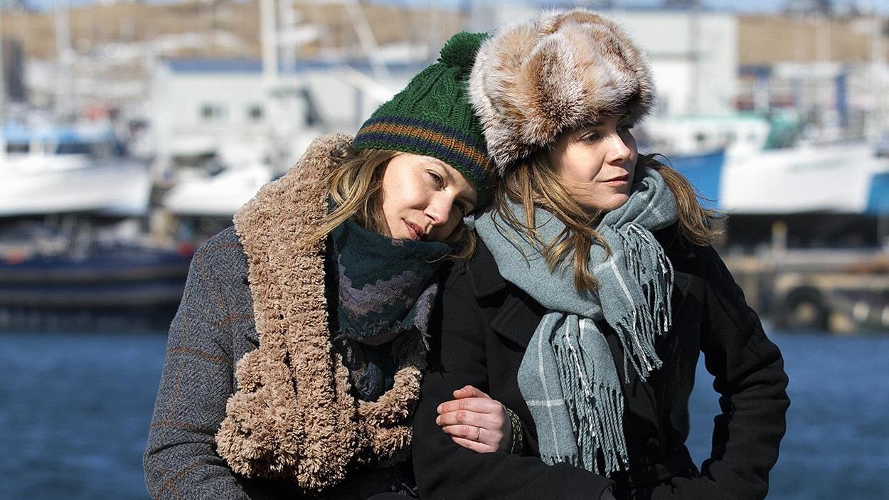 Magalie Lépine-Blondeau et Julie Perreault, assises côte à côte sur un quai, en hiver.