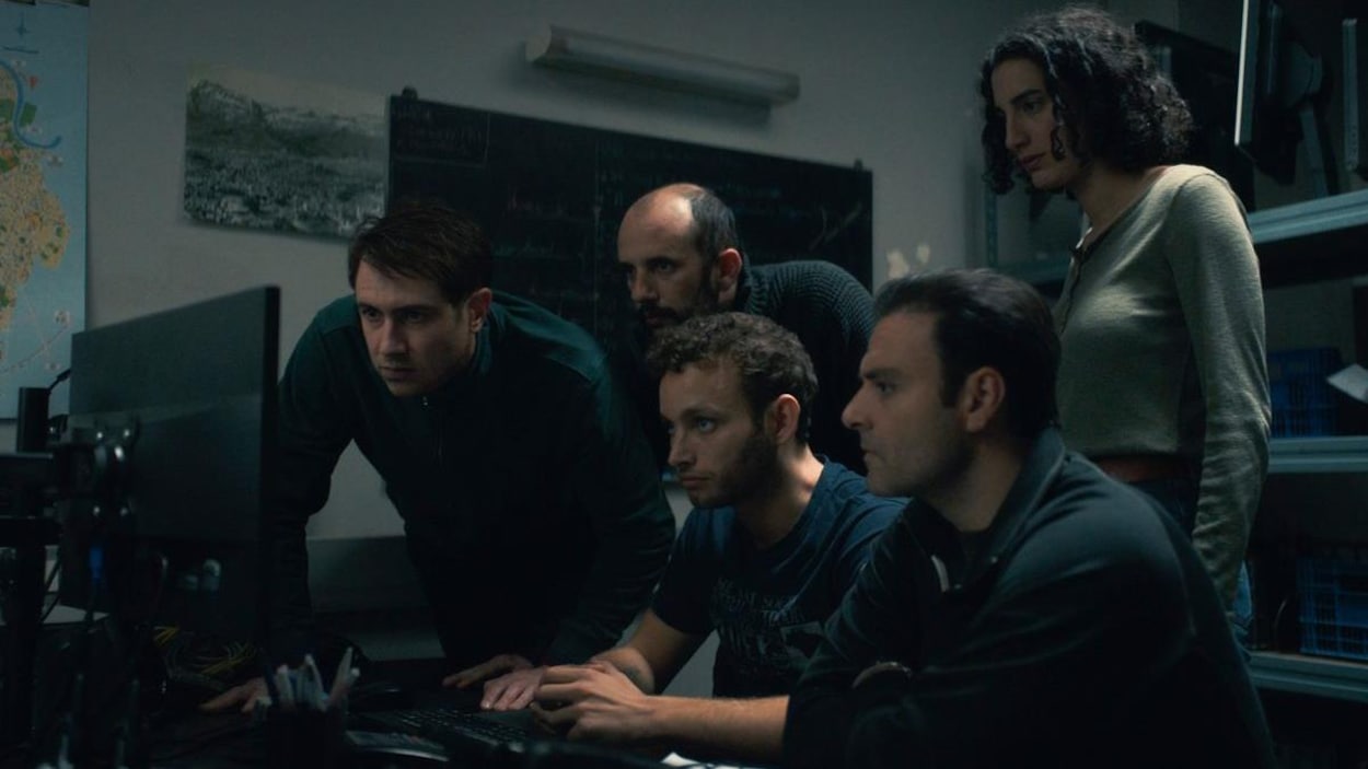 Un groupe d'hommes et une femme regardent l'écran d'un ordinateur. Un groupe d'hommes et une femme regardent l'écran d'un ordinateur.