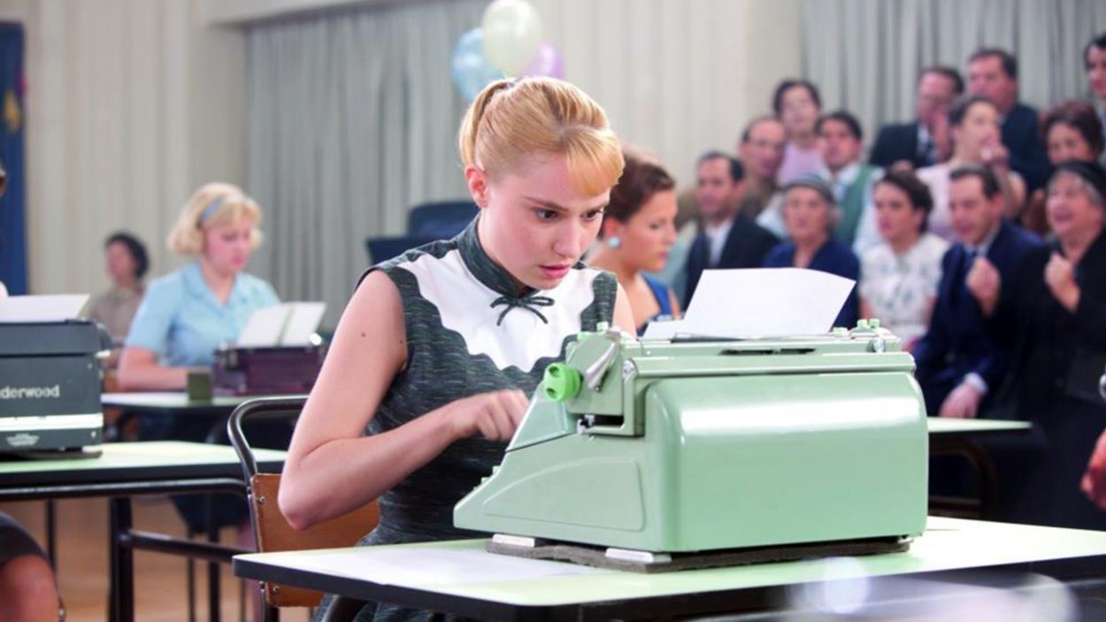 Une jeune fille penchée sur sa machine à écrire verte oâle, durant un concours de dactylographie Une jeune fille penchée sur sa machine à écrire verte oâle, durant un concours de dactylographie