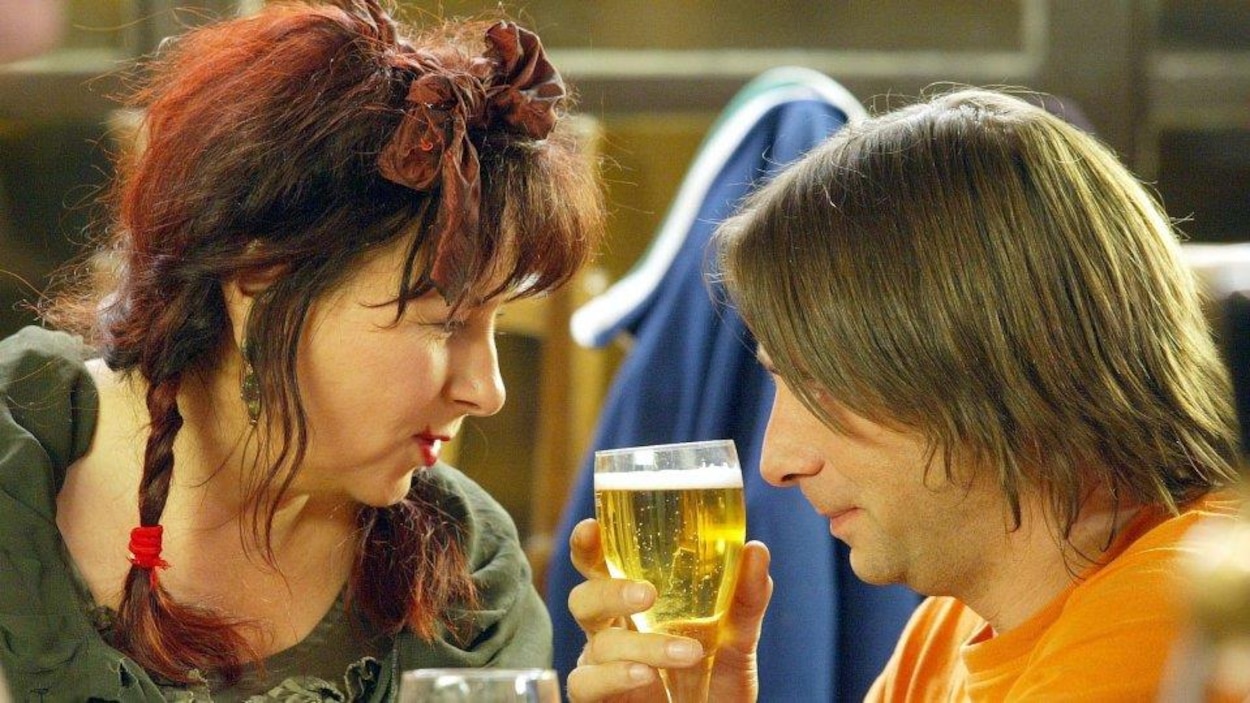 Une femme et un homme de profil se regardent, un verre de bière entre eux Une femme et un homme de profil se regardent, un verre de bière entre eux