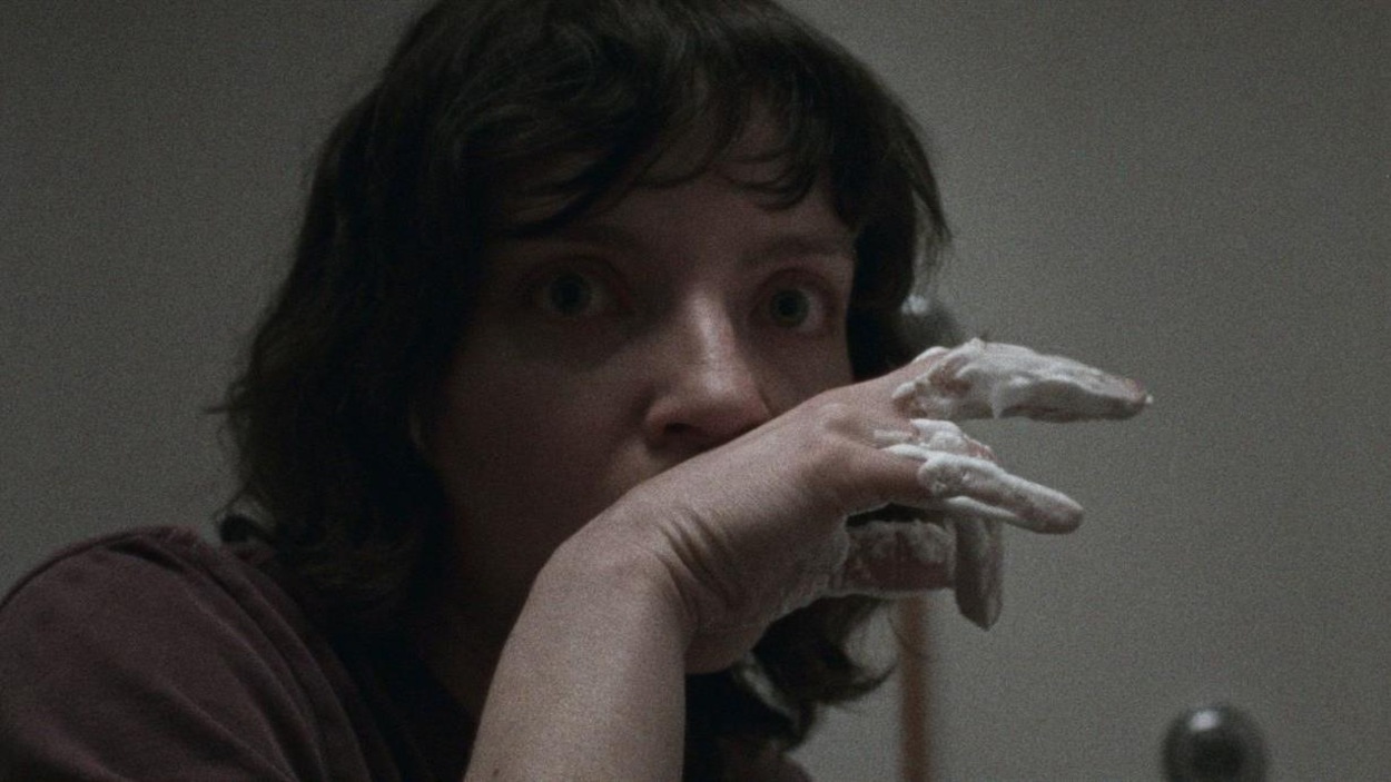 Une jeune femme (Larissa Corriveau), l'air effaré, la main devant la bouche. Une jeune femme (Larissa Corriveau), l'air effaré, la main devant la bouche.