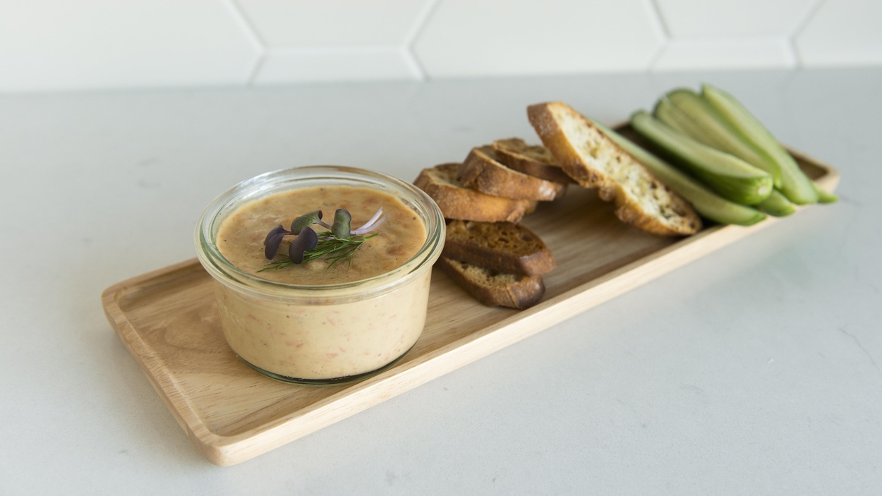 Le pot de mousse de saumon et des croûtons de pain sont disposés sur un petit cabaret en bois.