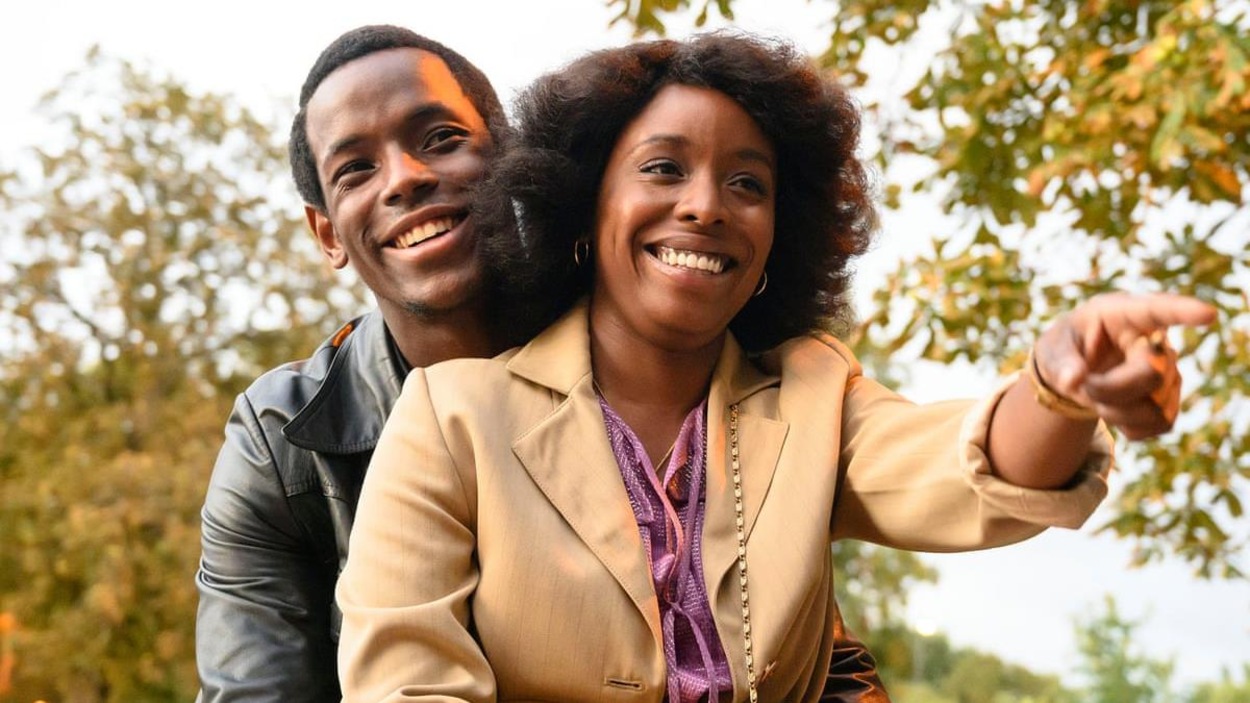 Un homme assis derrière une femme, tous deux souriant. Un homme assis derrière une femme, tous deux souriant.