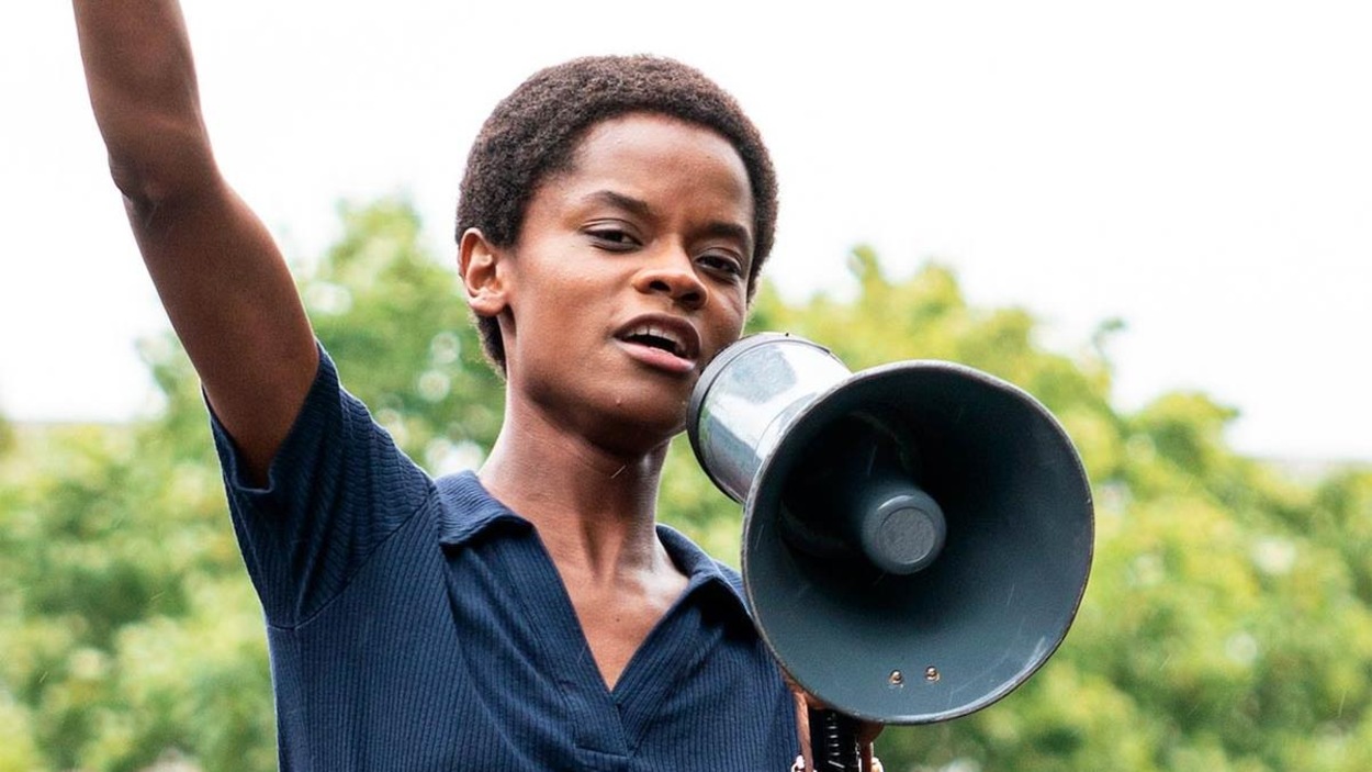 Une femme noire tient un mégaphone et lève le poing en l'air. Une femme noire tient un mégaphone et lève le poing en l'air.
