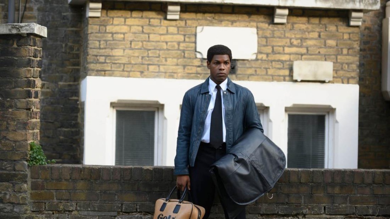 Un jeune homme (John Boyega) debout devant une rambarde en pierres. Un jeune homme (John Boyega) debout devant une rambarde en pierres.