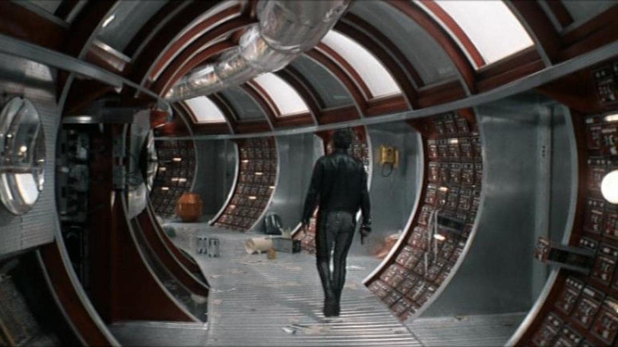 Un homme de dos dans un couloir rond de station spatiale.