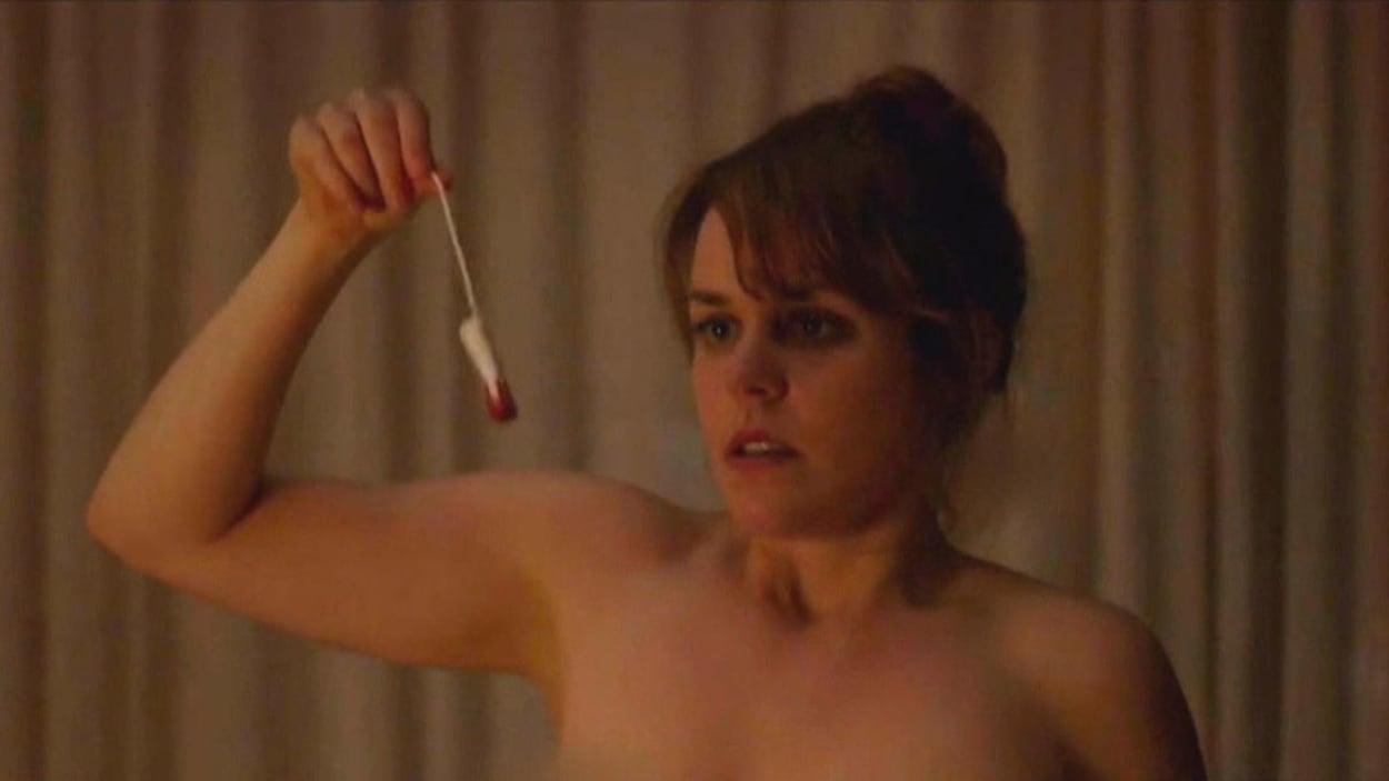 Une jeune femme nue regarde un tampon plein de sang, qu'elle tient par la ficelle. Une jeune femme nue regarde un tampon plein de sang, qu'elle tient par la ficelle.