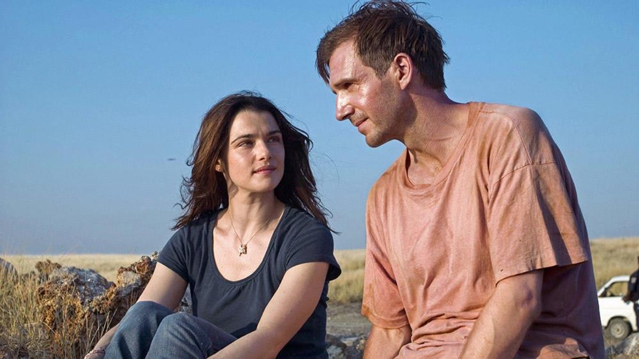 Une femme (Rachel Weisz) et un homme (Ralph Fiennes) assis à l'extérieur, dans une plaine, vêtus de t-shirt et de jeans. Une femme (Rachel Weisz) et un homme (Ralph Fiennes) assis à l'extérieur, dans une plaine, vêtus de t-shirt et de jeans.