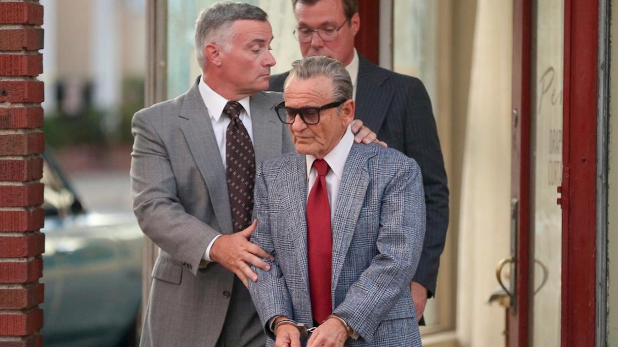 Un homme portant des menottes (Joe Pesci) entouré de deux autres hommes. Un homme portant des menottes (Joe Pesci) entouré de deux autres hommes.