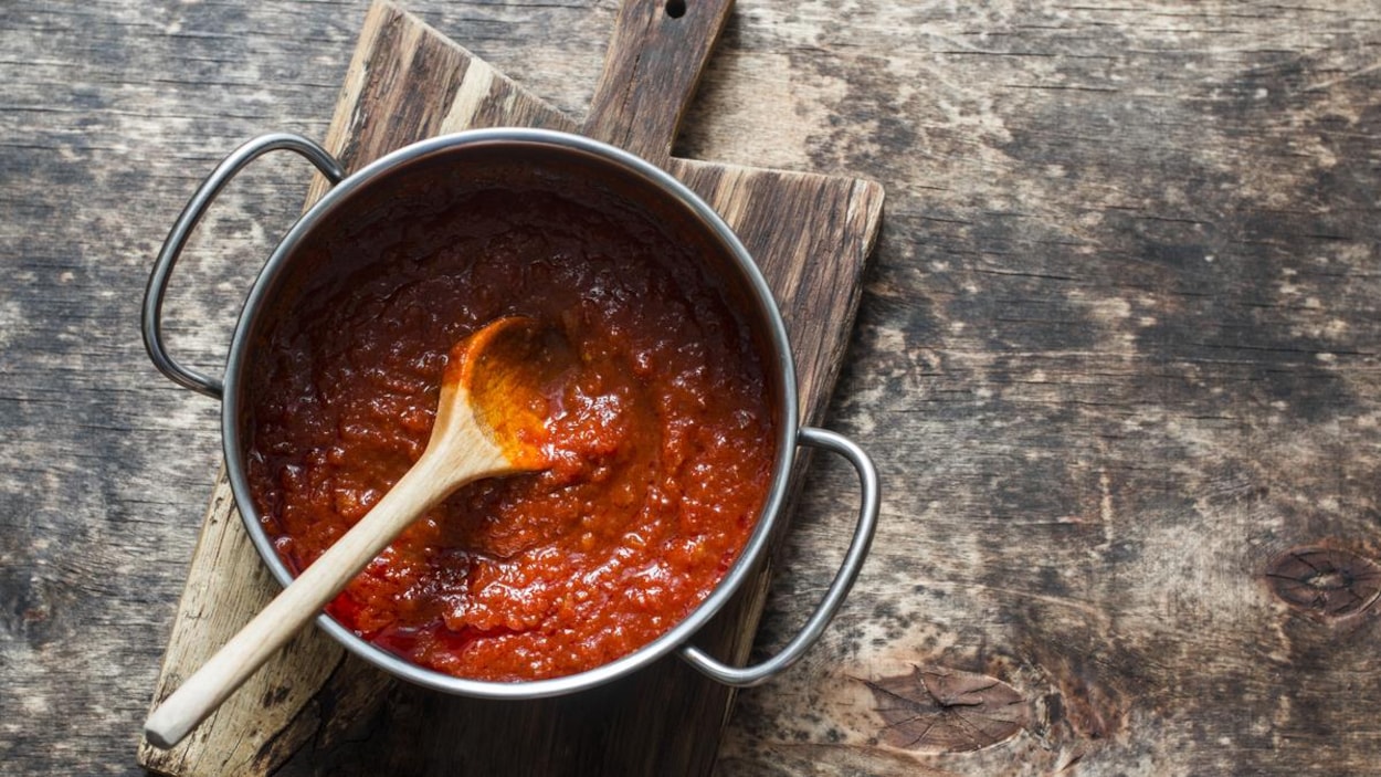 Sauce tomate maison dans un chaudron avec une cuillère en bois.