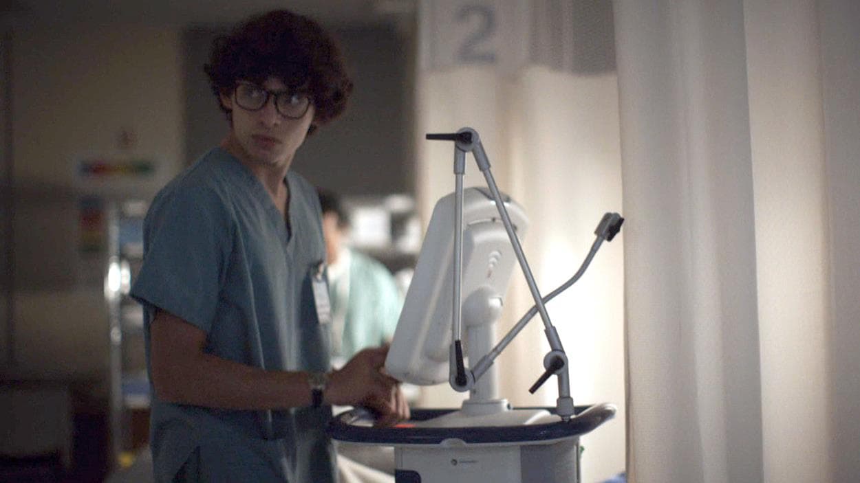 L'infirmier (Thomas Postigo) est devant l'écran d'un appareil médical.