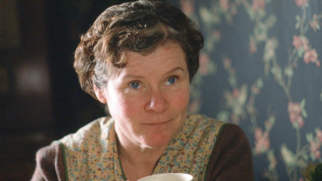 Une femme (Imelda Staunton), l'air bienveillant, assise, une tasse de thé dans la main. Une femme (Imelda Staunton), l'air bienveillant, assise, une tasse de thé dans la main.