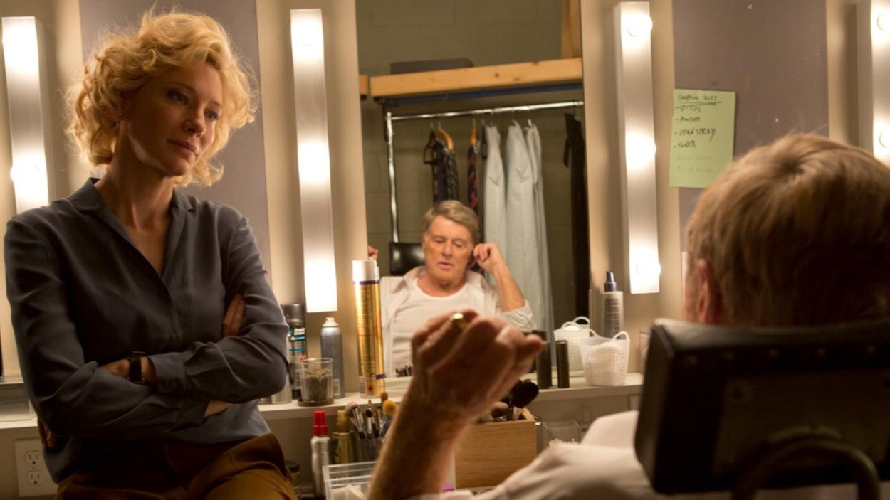 Une femme blonde face à un homme sur une chaise de maquillage. Une femme blonde face à un homme sur une chaise de maquillage.