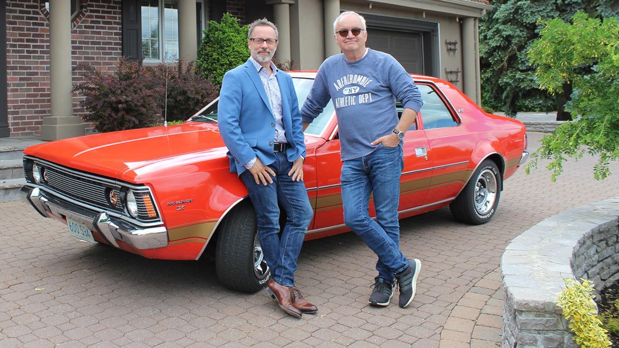 Serge Beauchemin et Michel Barrette devant une voiture rouge. Serge Beauchemin et Michel Barrette devant une voiture rouge.