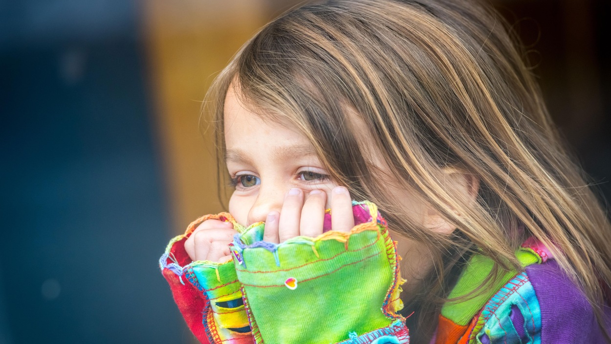 Une petite fille châtaine, dont les yeux sont verts, regarde par la fenêtre. Une petite fille châtaine, dont les yeux sont verts, regarde par la fenêtre.
