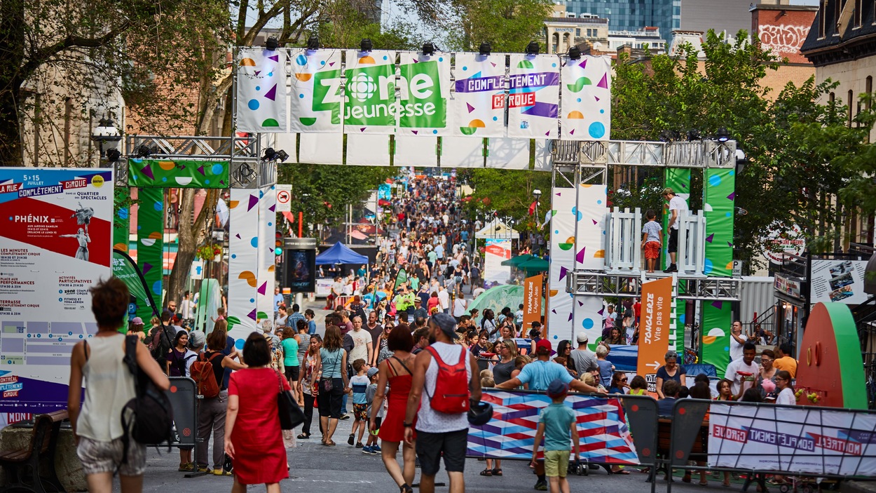Une foule se promène dans une rue dans la section zone Jeunesse de Montréal Complètement Cirque. Une foule se promène dans une rue dans la section zone Jeunesse de Montréal Complètement Cirque.
