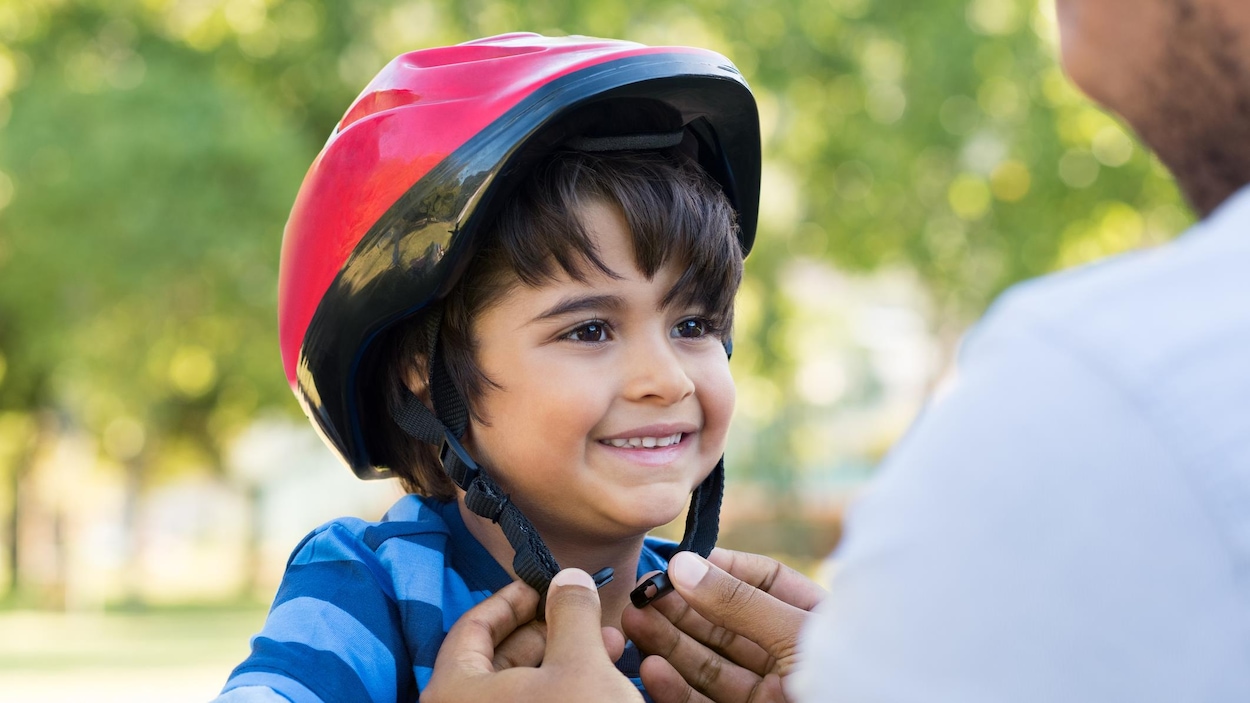 Un père aide son fils à mettre son casque de vélo. Un père aide son fils à mettre son casque de vélo.