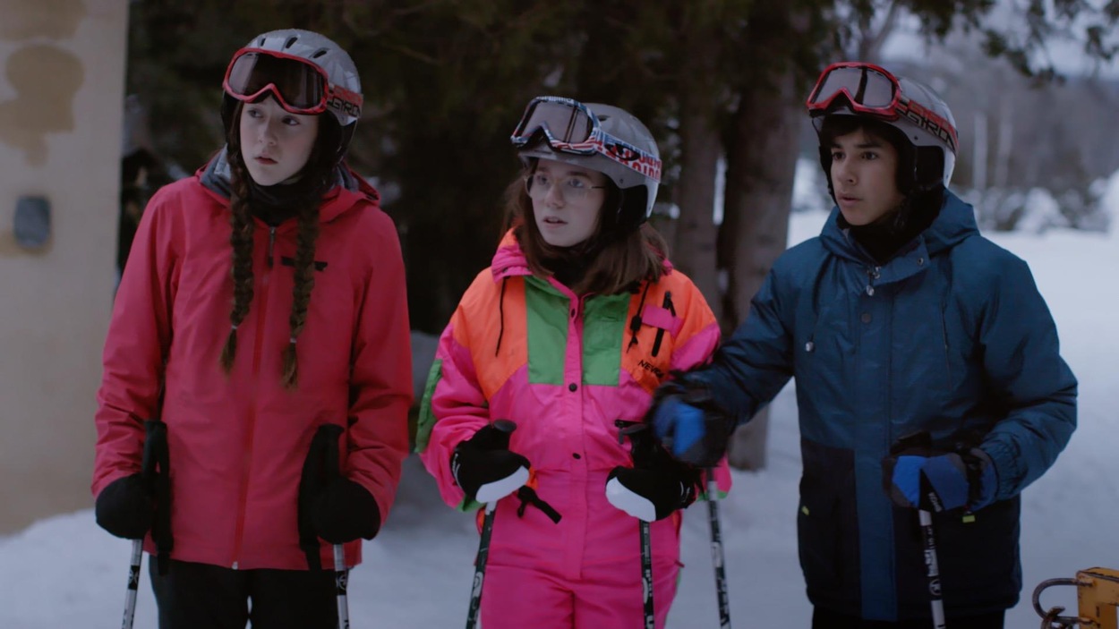 Les trois amis sont arrêtés et regardent une scène intrigante qui se passe hors champs.