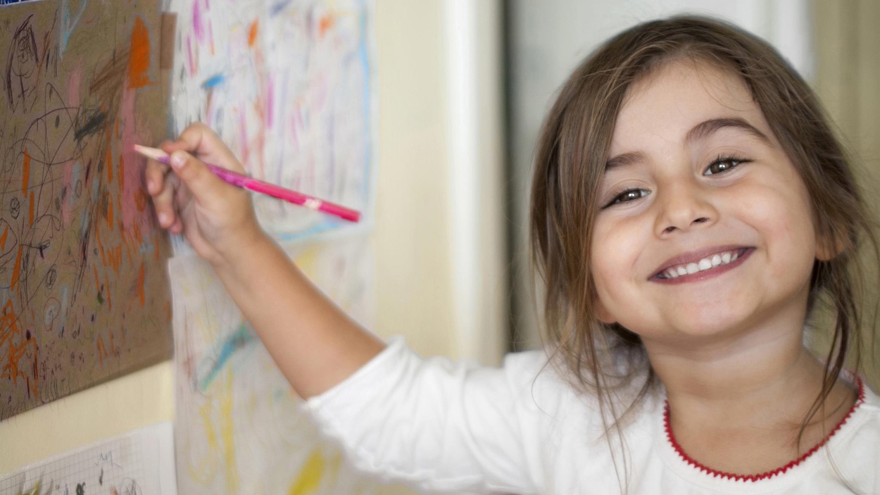 Une petite fille souriante dessine sur un mur. Une petite fille souriante dessine sur un mur.