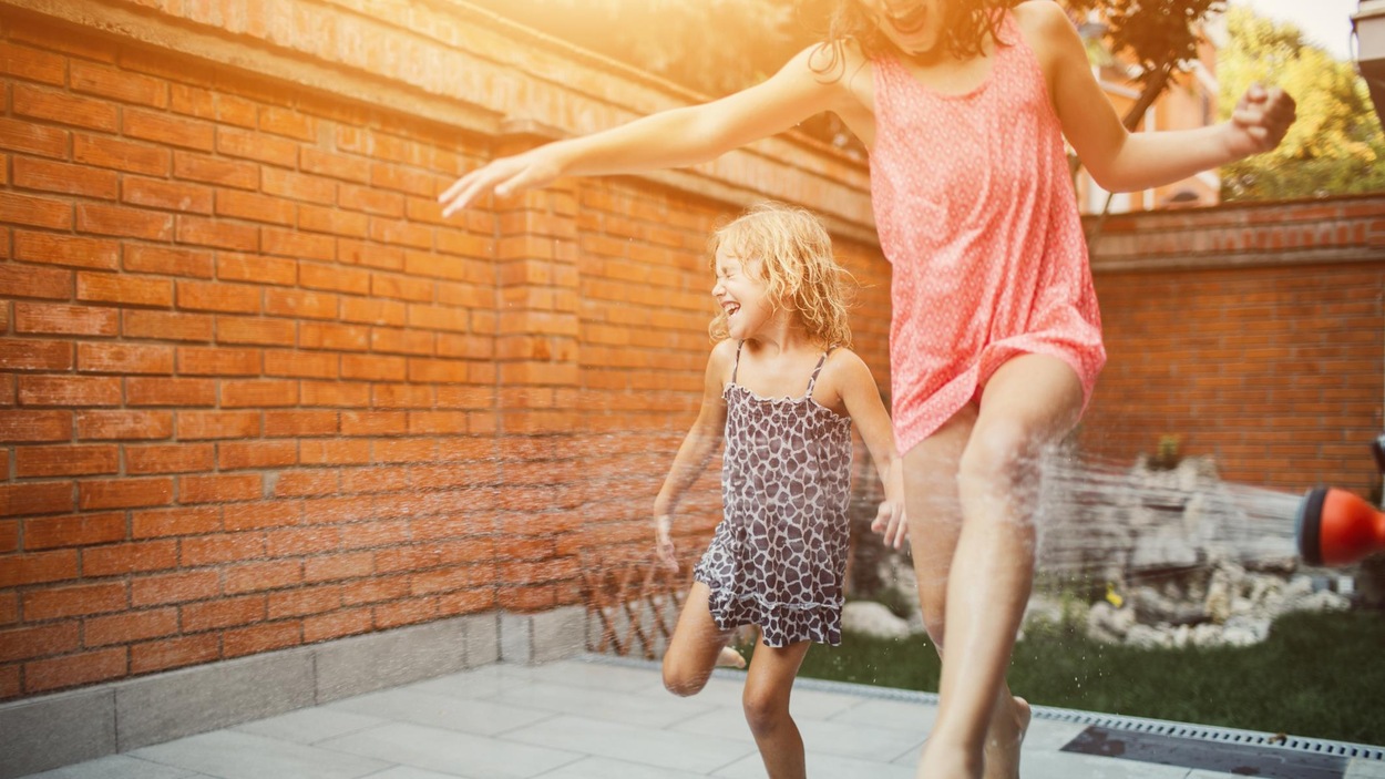 Une mère et sa fille se font arroser par un boyau d'arrosage. Une mère et sa fille se font arroser par un boyau d'arrosage.