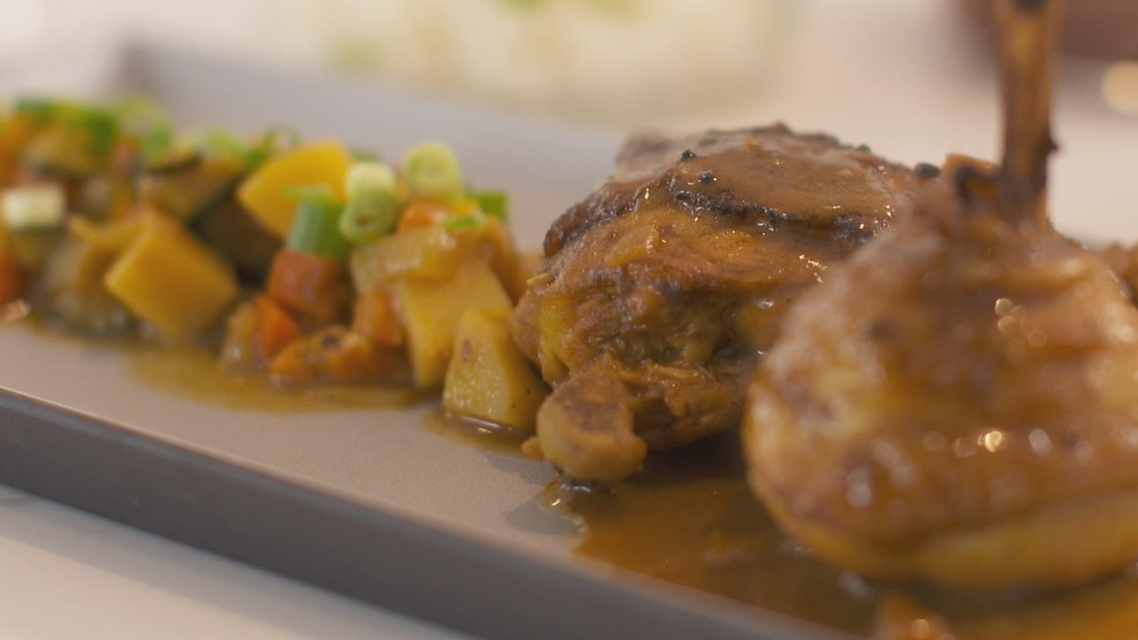 Un plat composé de poulet, de légumes et de sauce colombo Un plat composé de poulet, de légumes et de sauce colombo