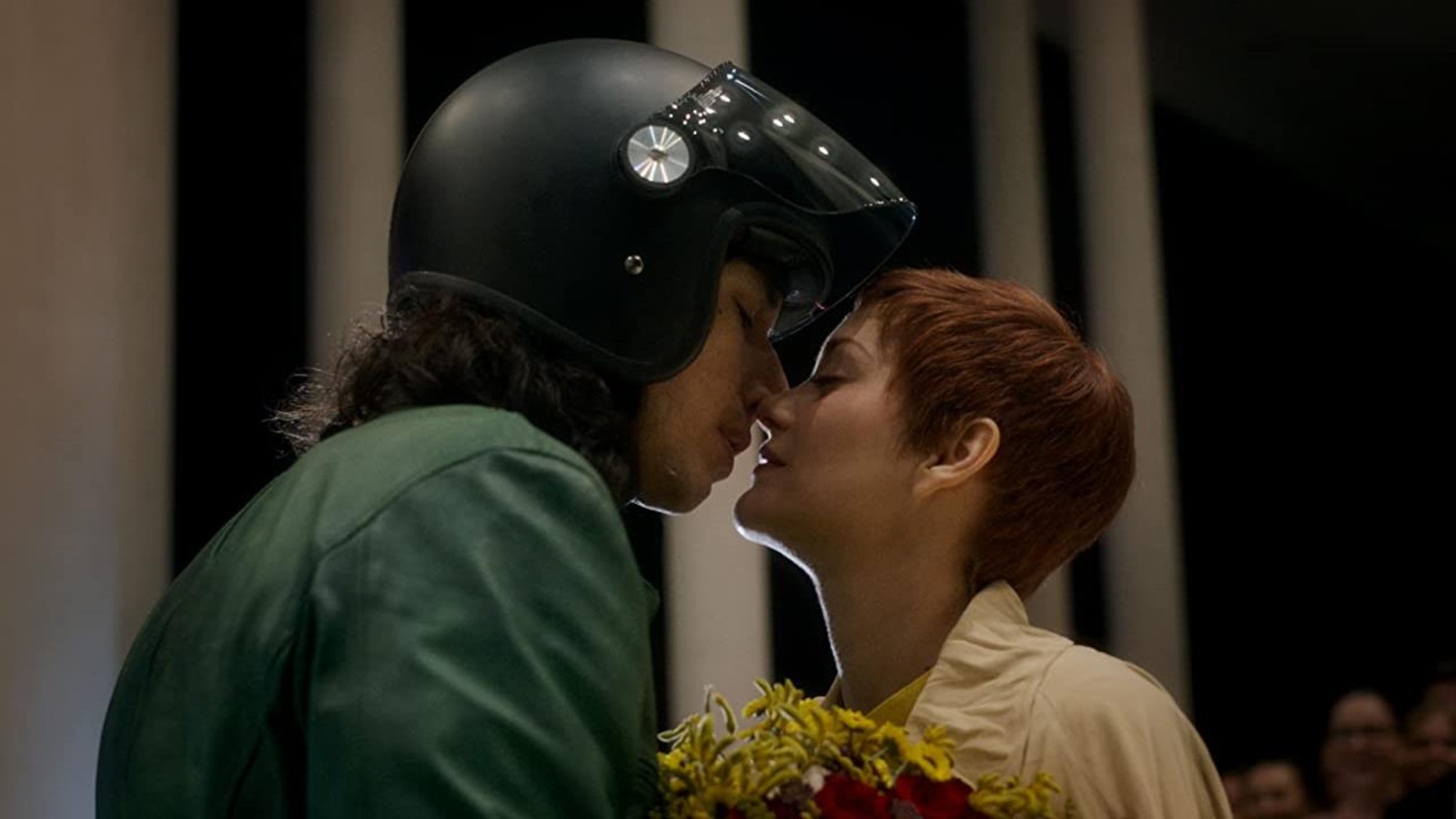 Une homme vêtu d'un casque de moto embrasse une femme.
